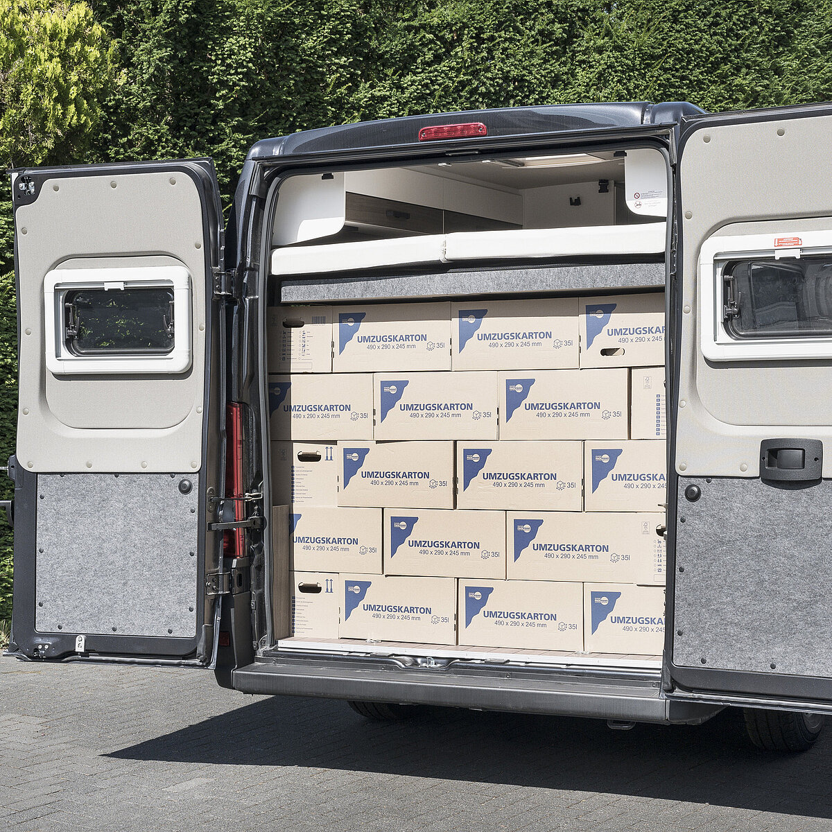 Heckstauraum im VANTourer Kastenwagen: Beladung mit Umzugskartons unter dem hochgefahrenen Hubbett
