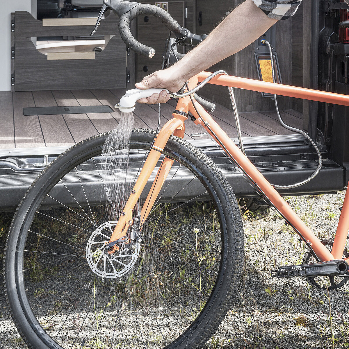 Fourgon VANTourer : nettoyage des vélos directement après la randonnée grâce à la douche extérieure