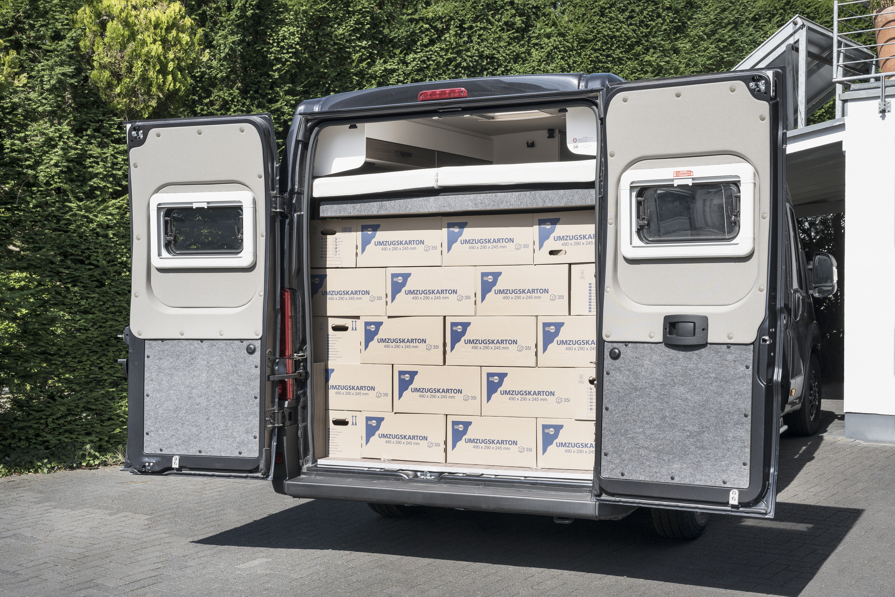 Großer Heckstauraum im VANToutrer Campervan – beladen mit Umzugskartons unter dem optionalen Hubbett